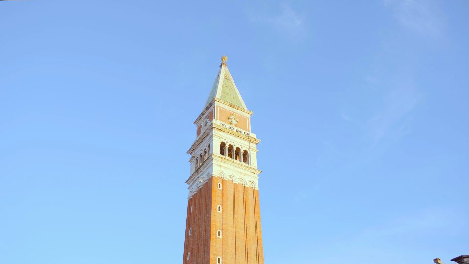 L’alto campanile si riflette sull’asfalto vicino al museo di Palazzo Ducale
