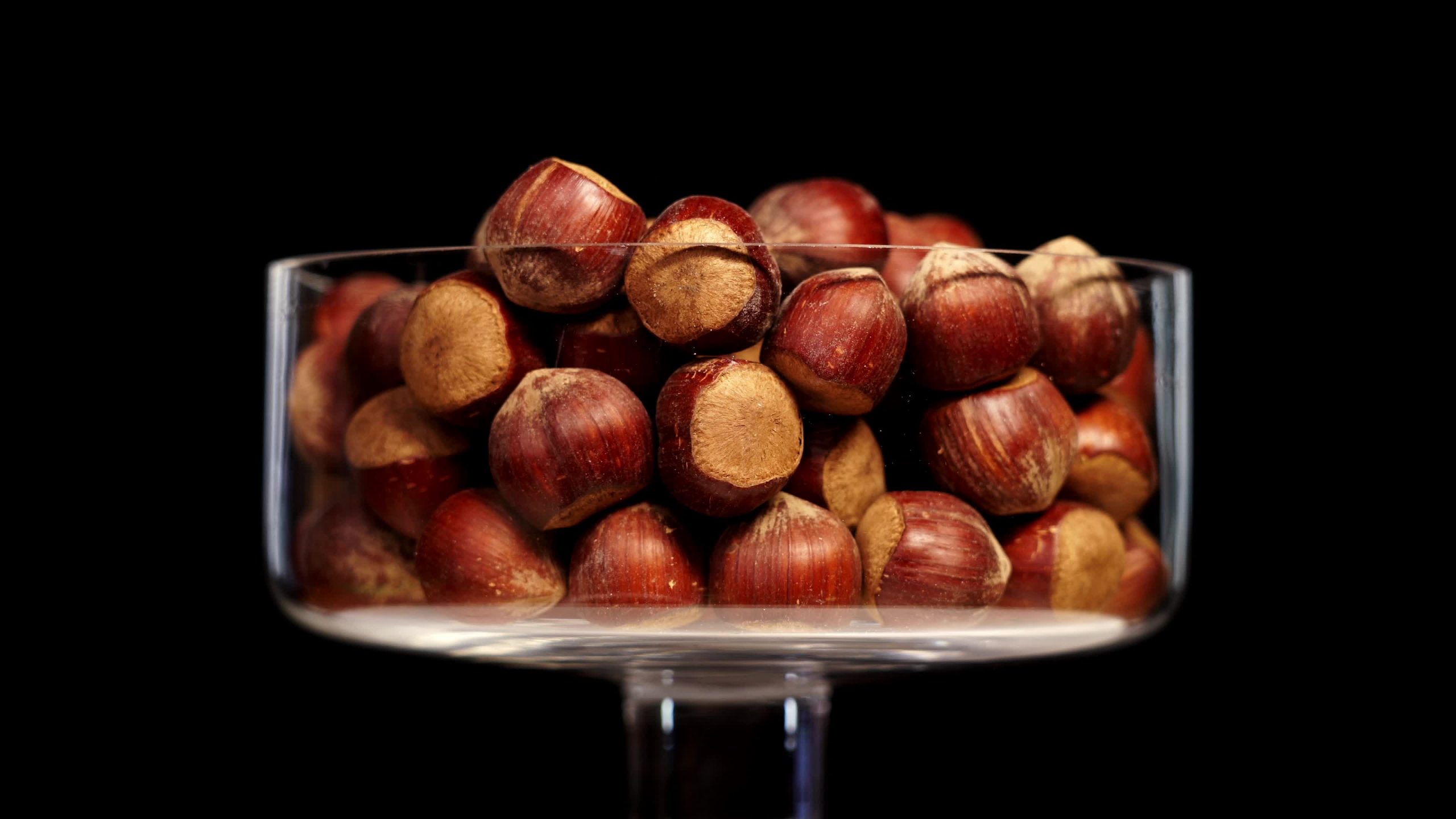 Bowl full of raw peeled hazelnuts turns on black background