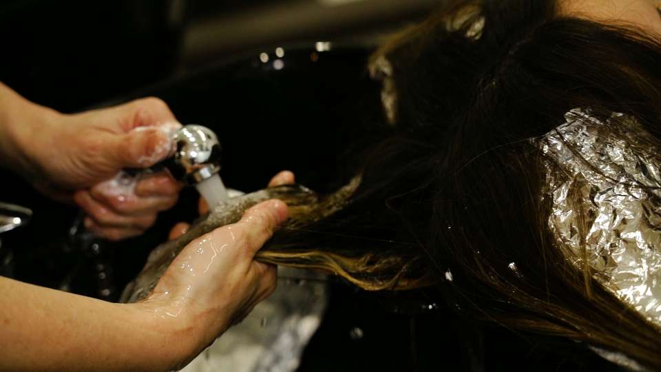 Il parrucchiere lava i capelli della signora con acqua nel salone di bellezza