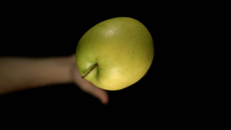 La mano della persona lancia una mela di colore verde e la cattura