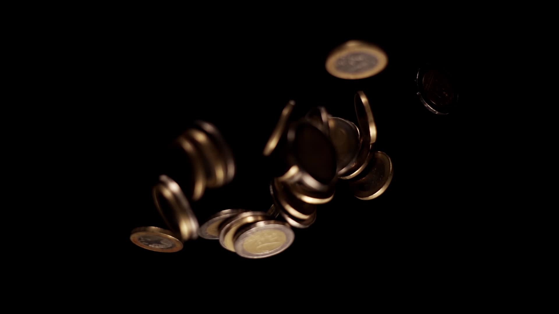 Piccole monete d’oro e d’argento cadono riflettendo la luce