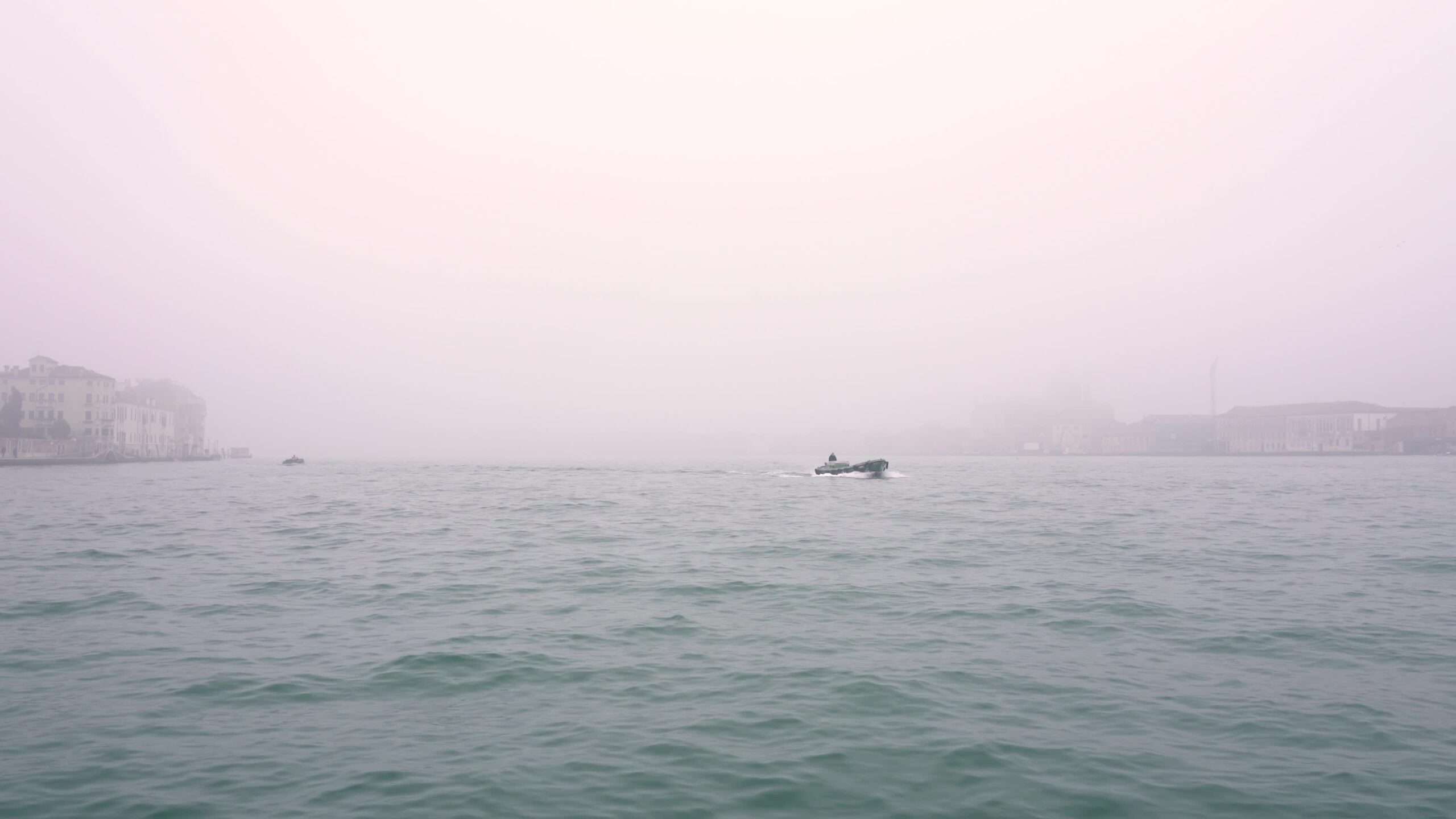 Piccolo motoscafo naviga sull’acqua della laguna veneta nella nebbia