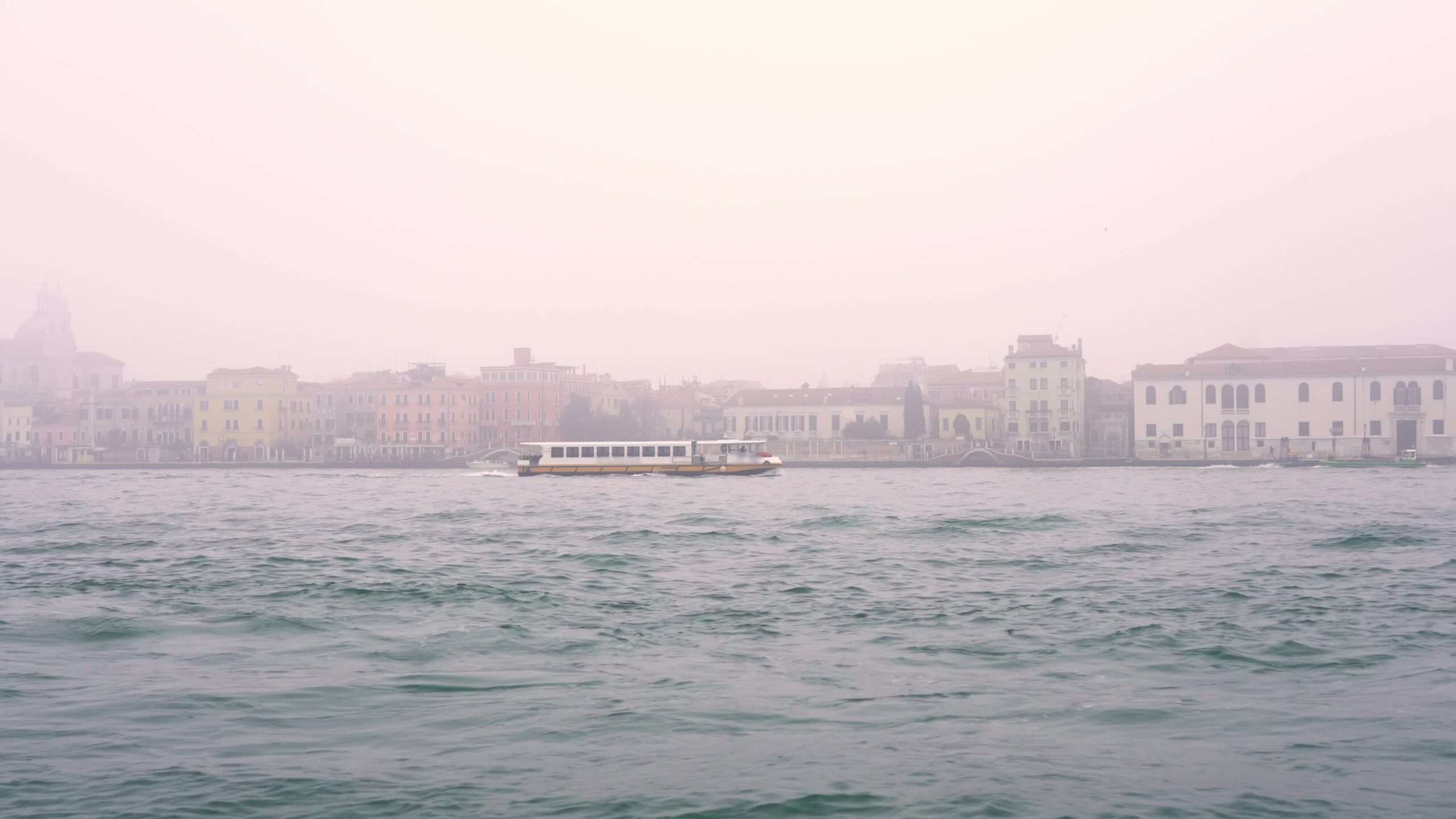 Velocità turistica della barca da diporto contro la città antica nella nebbia