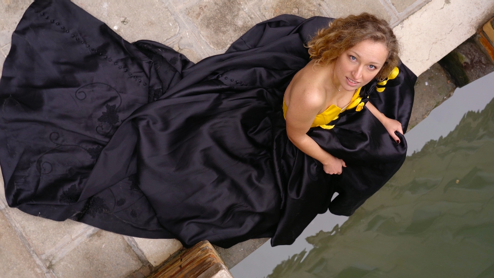 Splendida modella in abito di carnevale siede dal canale di venezia