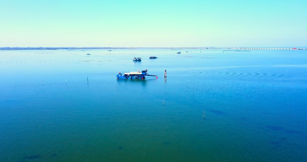 Laguna con acqua blu pulita e barche per la pesca di molluschi