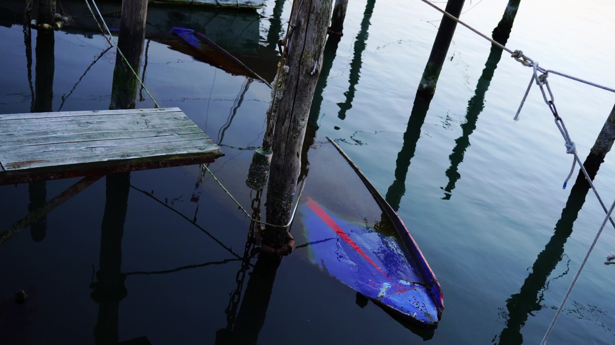 Grande carcassa di barca affondata vicino a motoscafi in legno ormeggiati