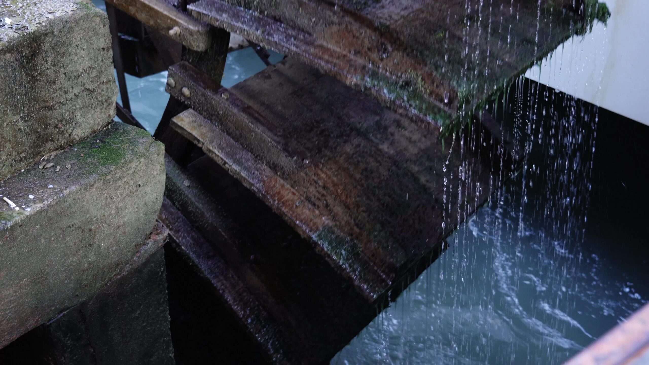Il mulino ad acqua in legno obsoleto di colore marrone ruota nell’acqua