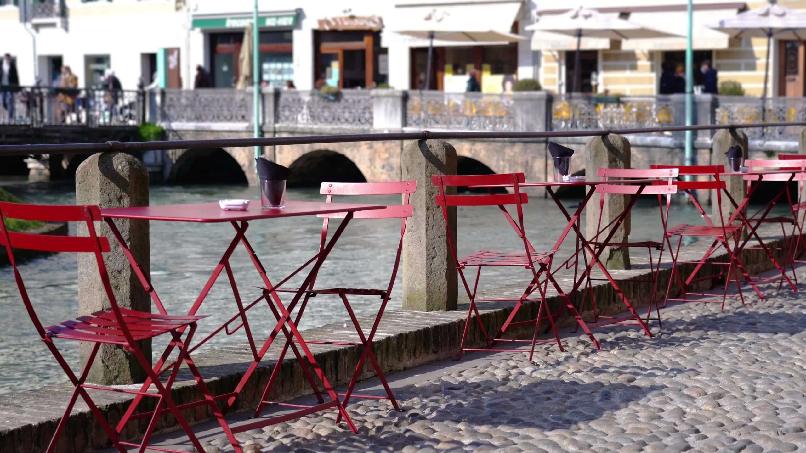 Tavoli e sedie rossi del caffè locale lungo il fiume sul marciapiede