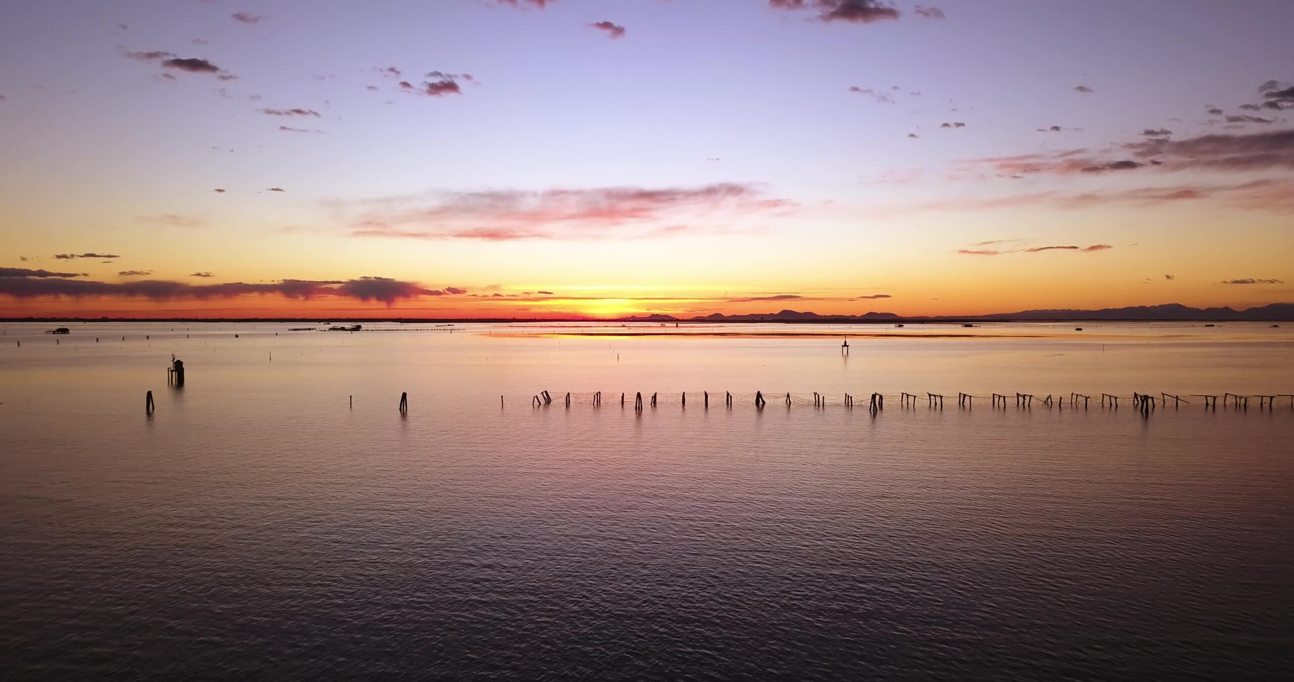 Sunset light reflects on sea water with shellfish farm nets