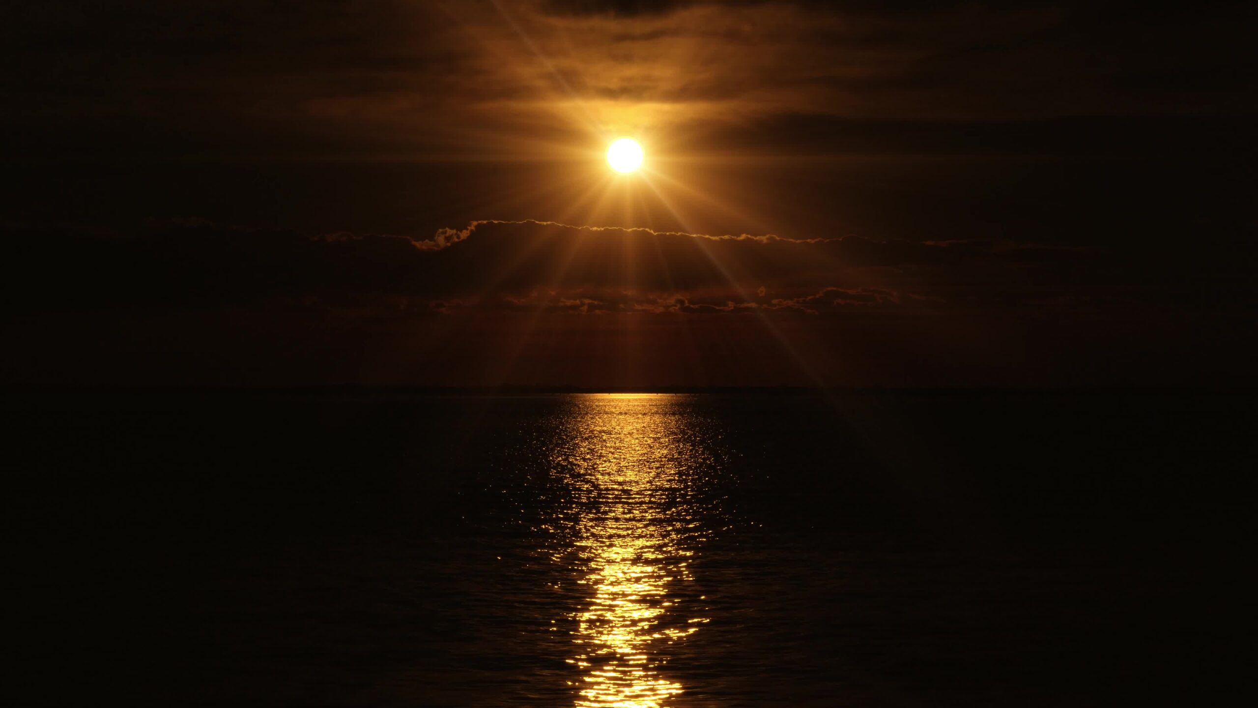 La luce radiosa del disco solare si riflette sull’acqua in un mare sconfinato
