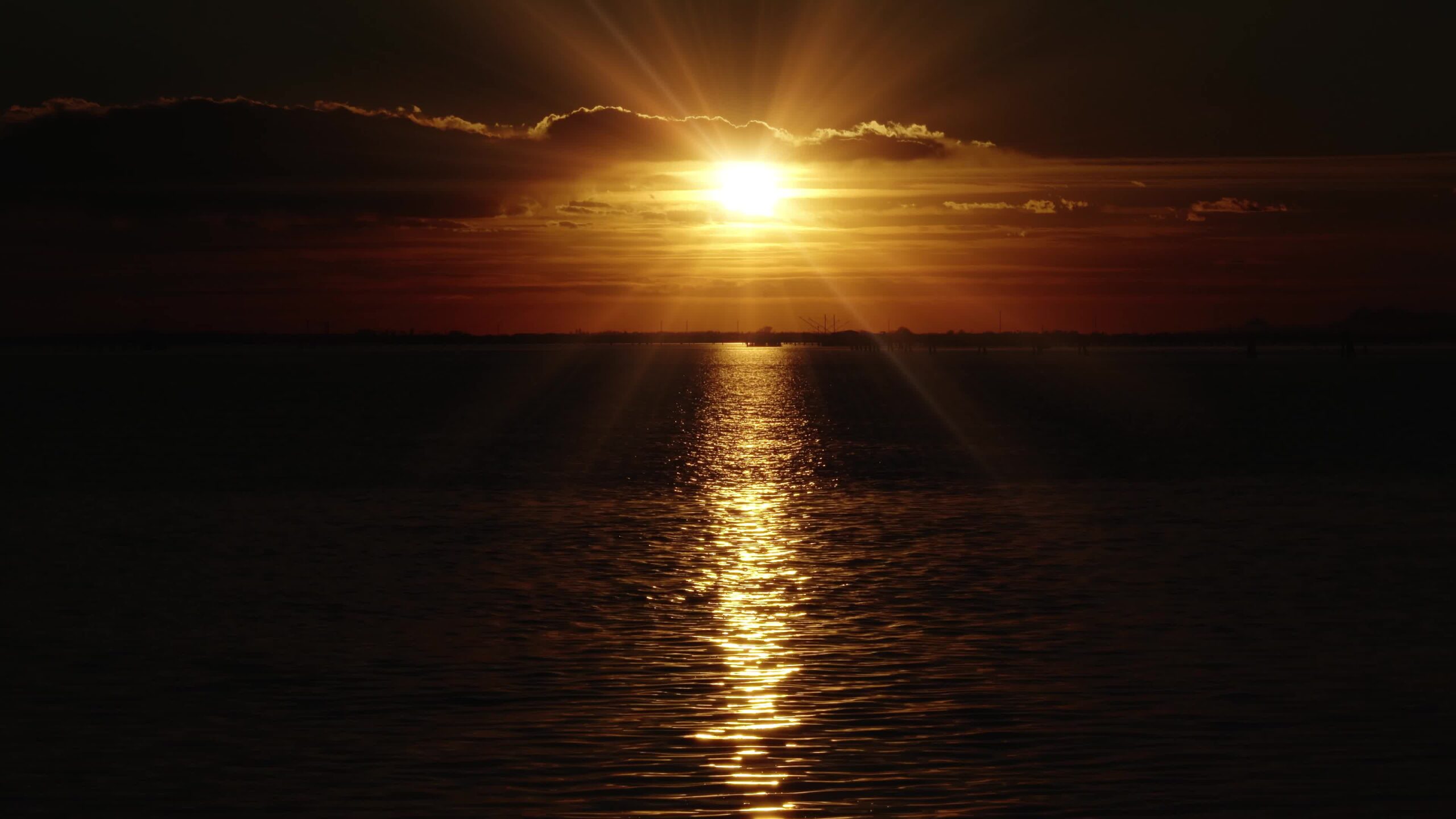Il sole che tramonta all’orizzonte illumina il mare scuro con l’acqua increspata