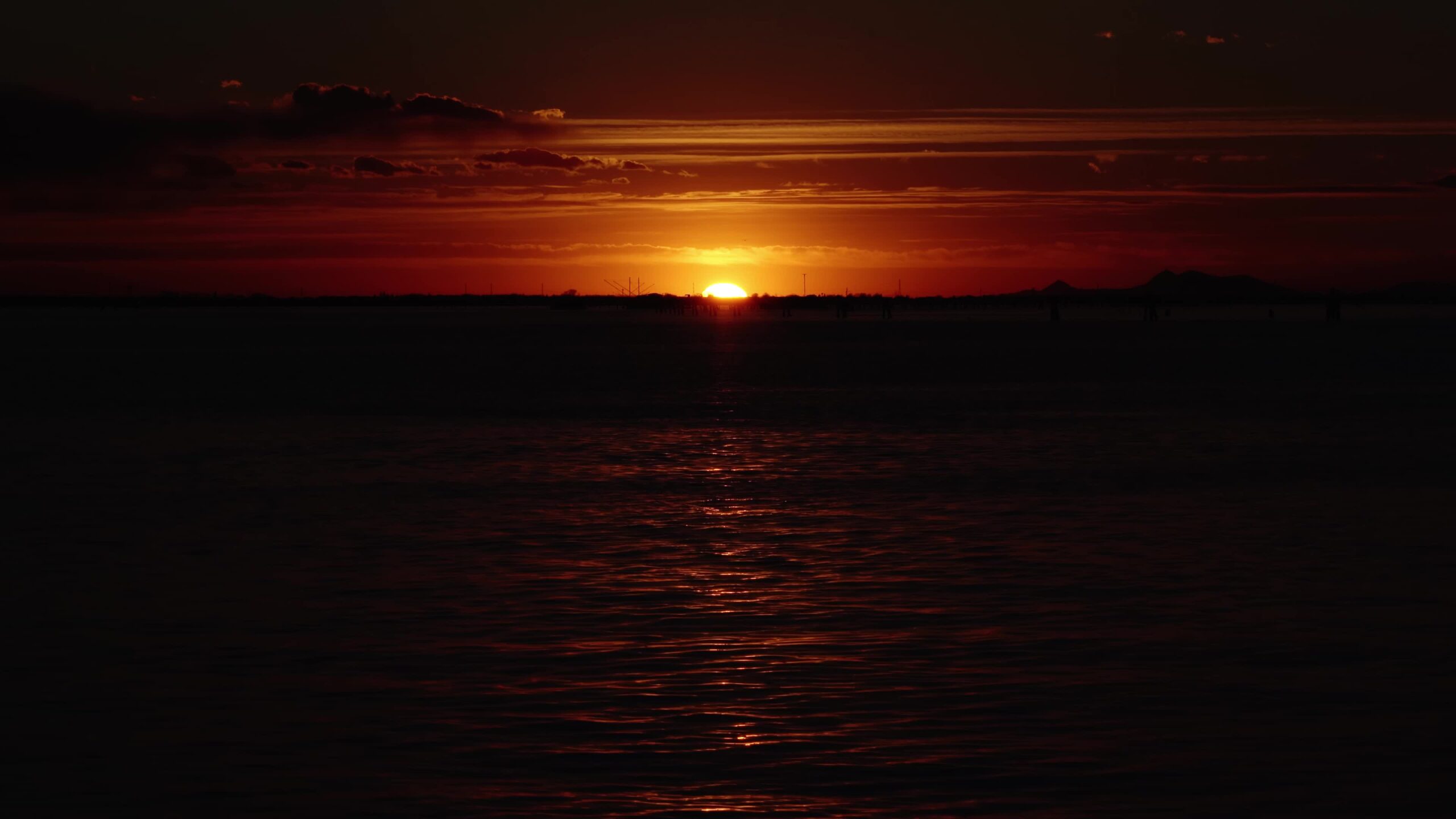 Il sole al tramonto si riflette sulla laguna creando un percorso di luce solare