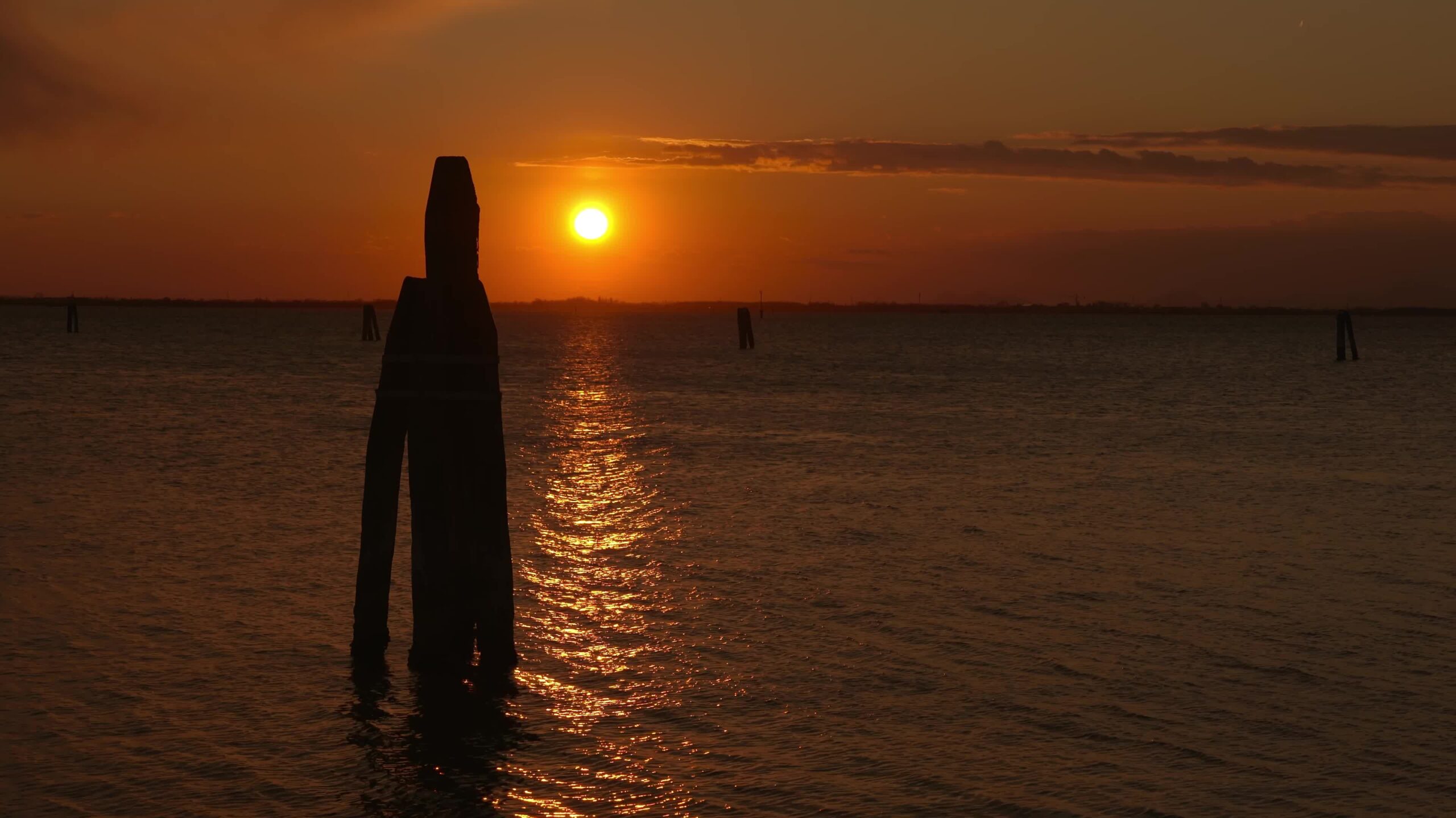 Indicatore della via navigabile del pilastro nella laguna veneziana scura al tramonto