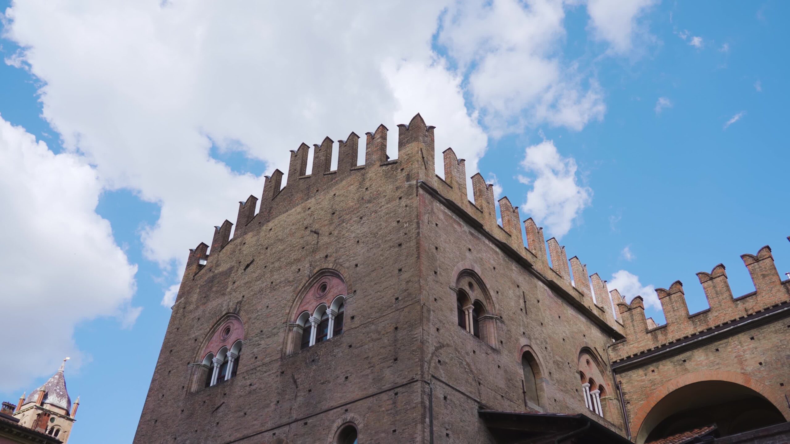 Ancient Palazzo Re Enzo top against blue sky in Bologna