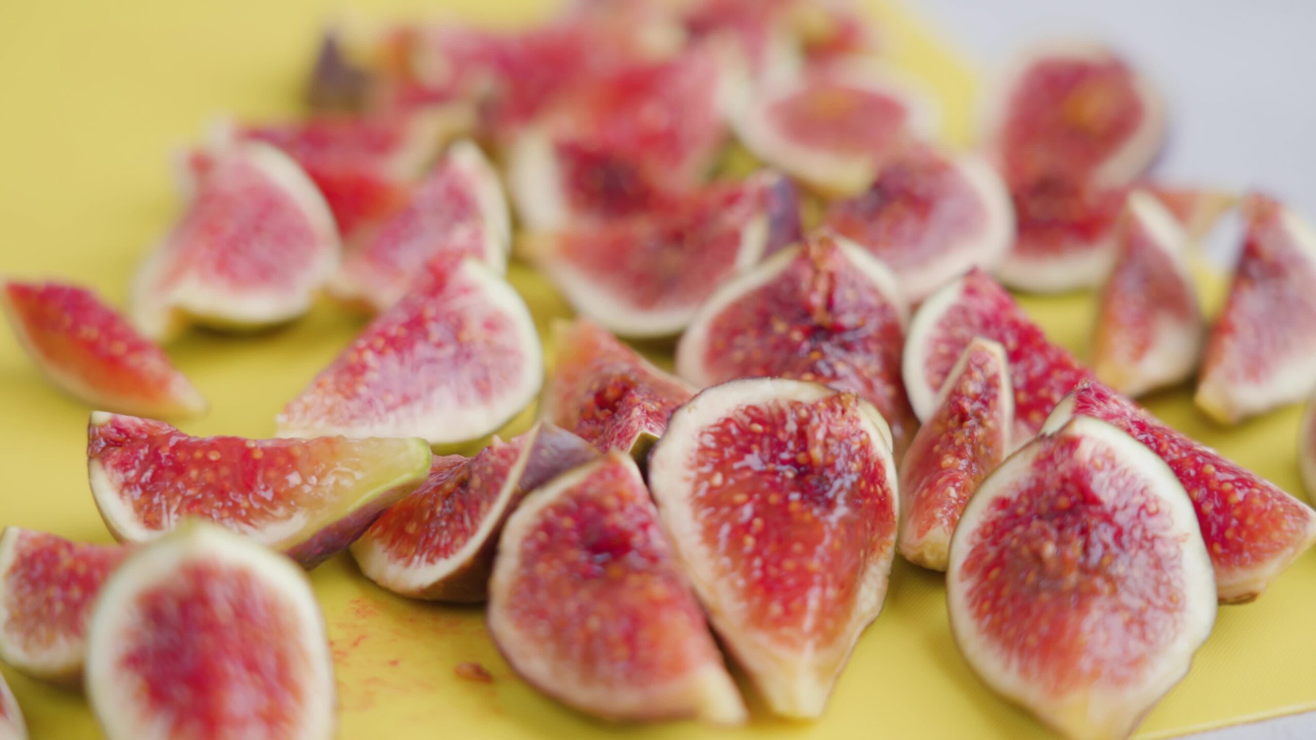 Tasty fresh fig slices lie on yellow cutting board