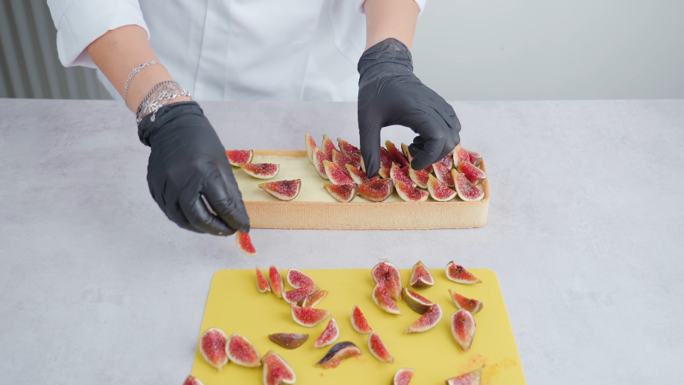 Baker decorates squared biscuit putting fig slices on top