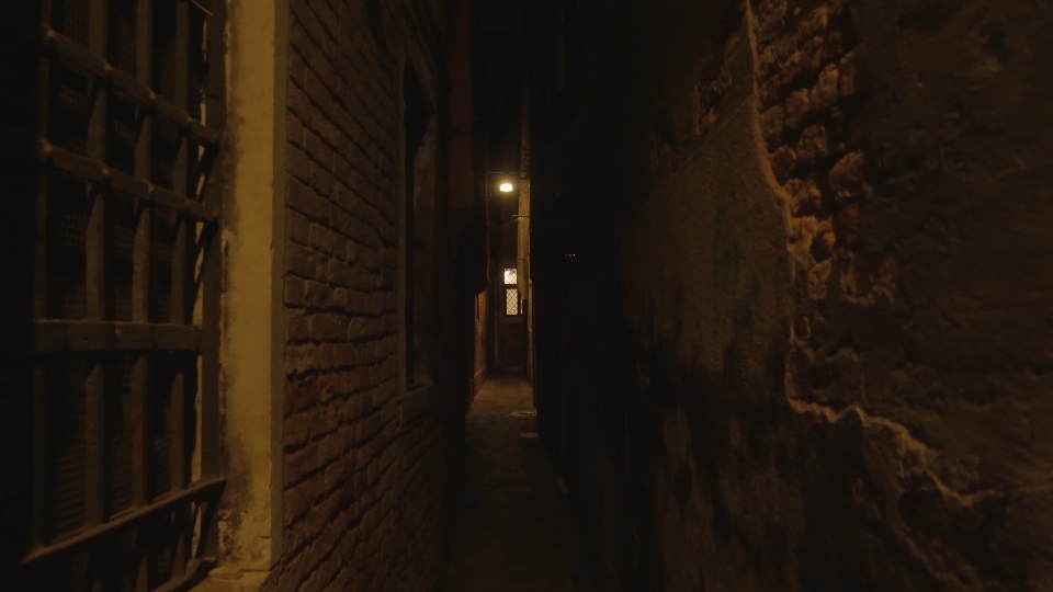 Stretto passaggio veneziano scuro con lampada illuminante