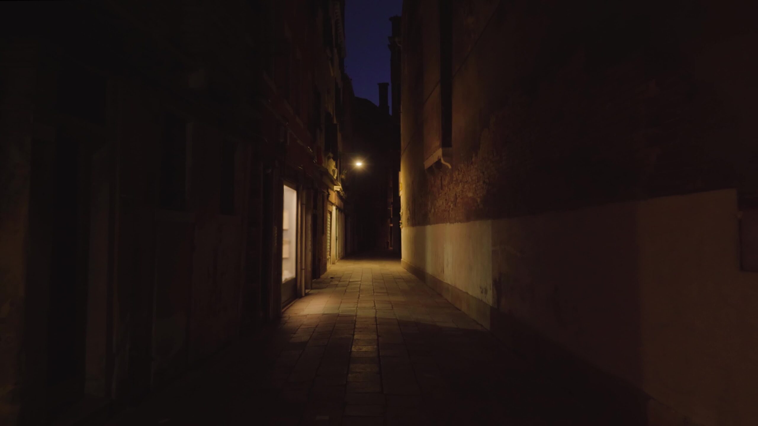 Strada vuota scura lunga e stretta illuminata da finestra e lampada