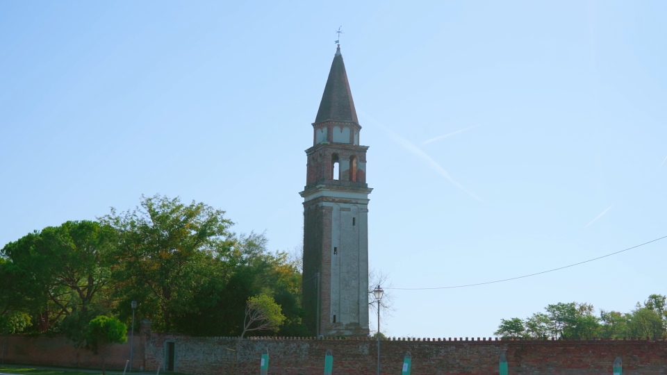 Il campanile della chiesa con recinzione in mattoni si erge tra gli alberi