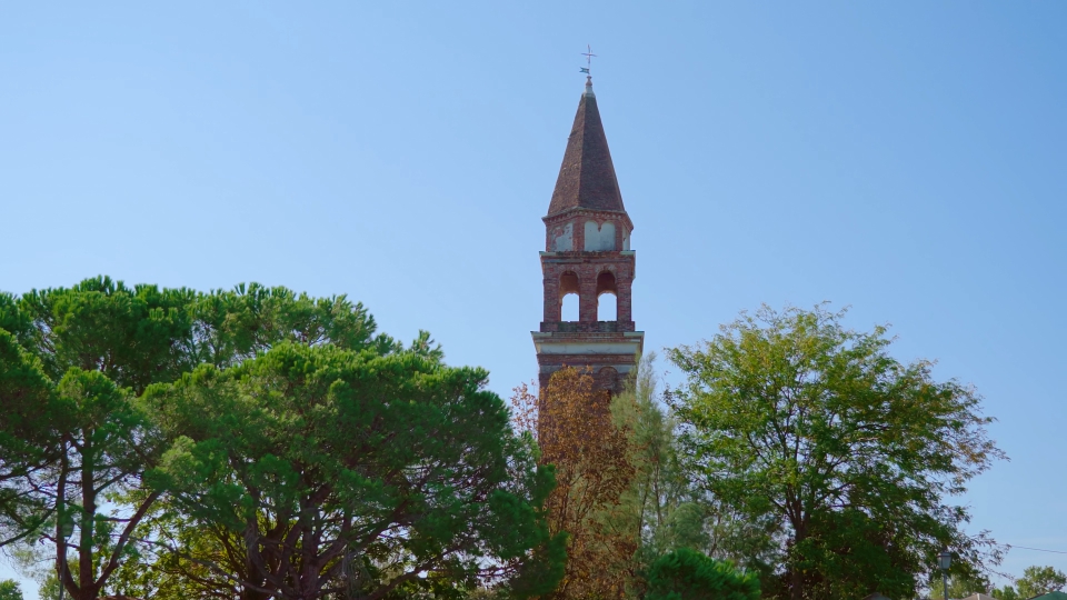 L’alto campanile della chiesa con recinzione in mattoni si erge tra il parco