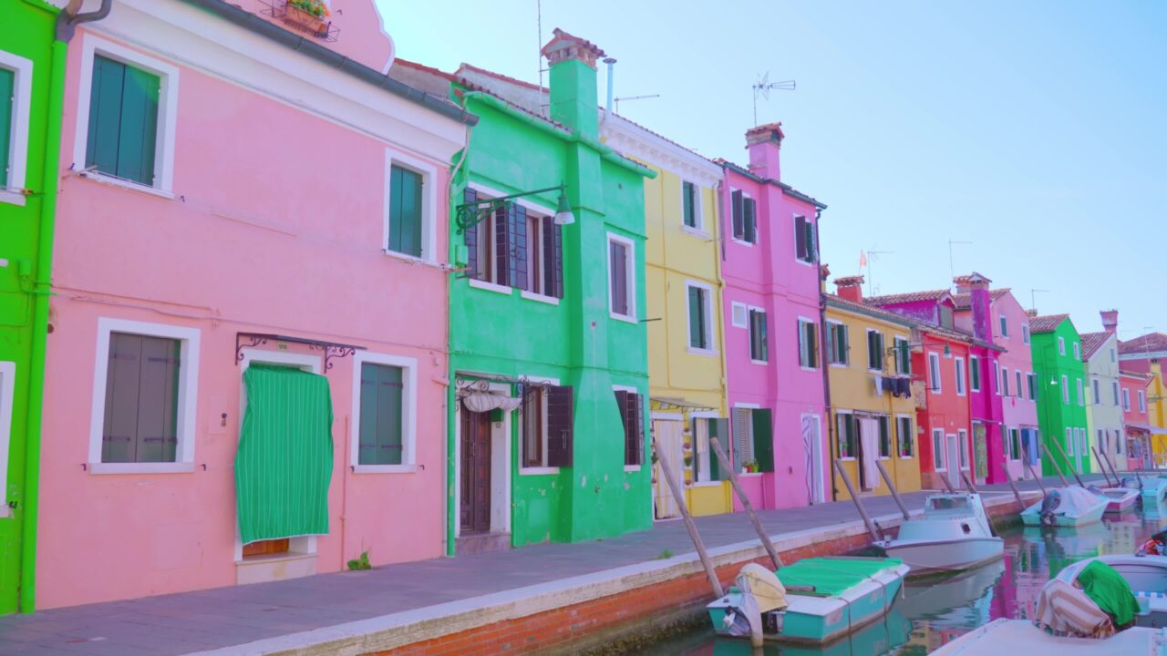 Luminose case multicolori stanno in fila lungo il canale dell’acqua