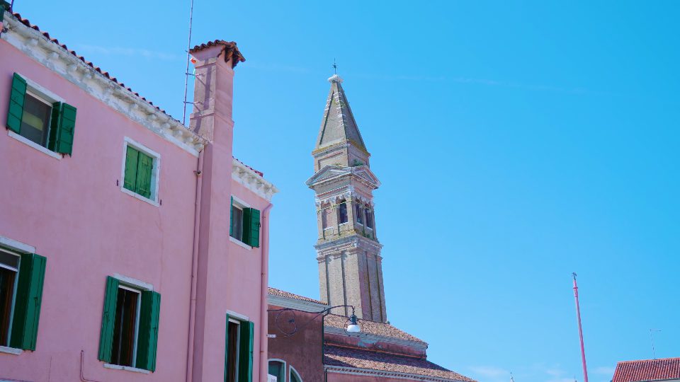 Campanile della chiesa visto da dietro le case dai colori vivaci