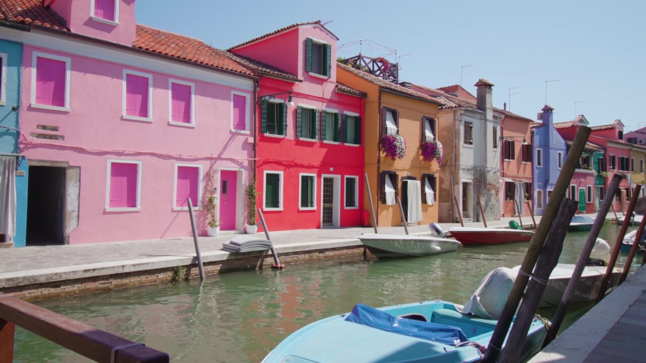 Case colorate sulla riva del canale d’acqua di Burano con barche