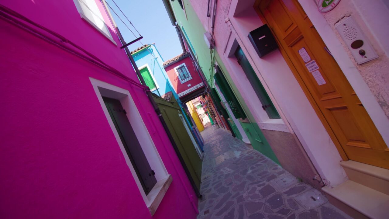 Stradina in ombra tra case colorate a Burano