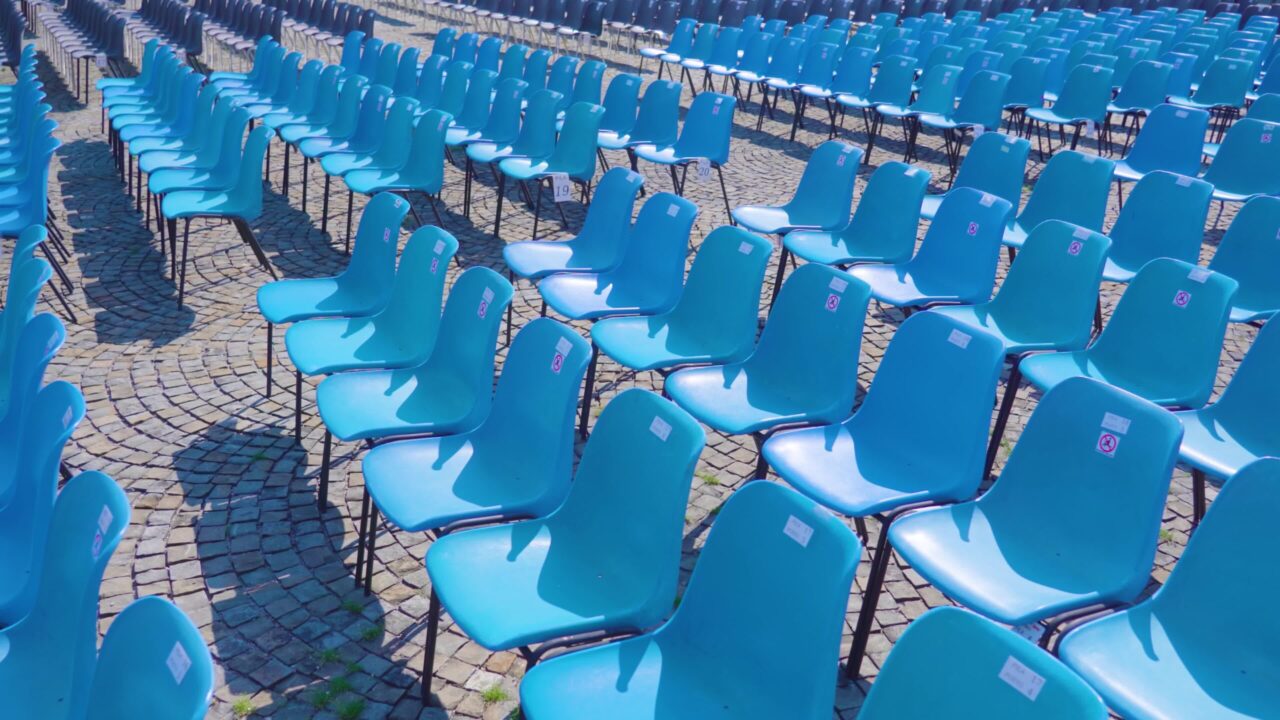 Sedie di plastica blu allineate in fila per l’osservazione degli eventi