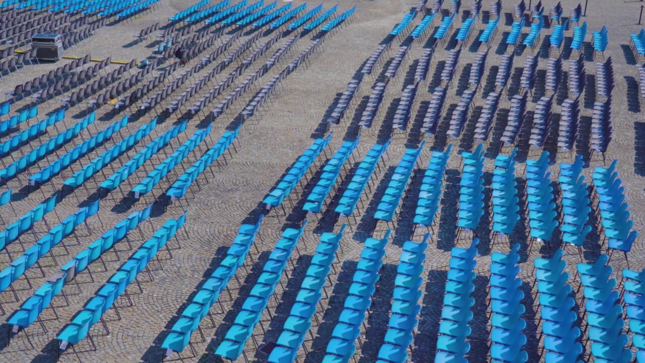 Lunghe file di sedie di plastica blu per gli spettatori in città
