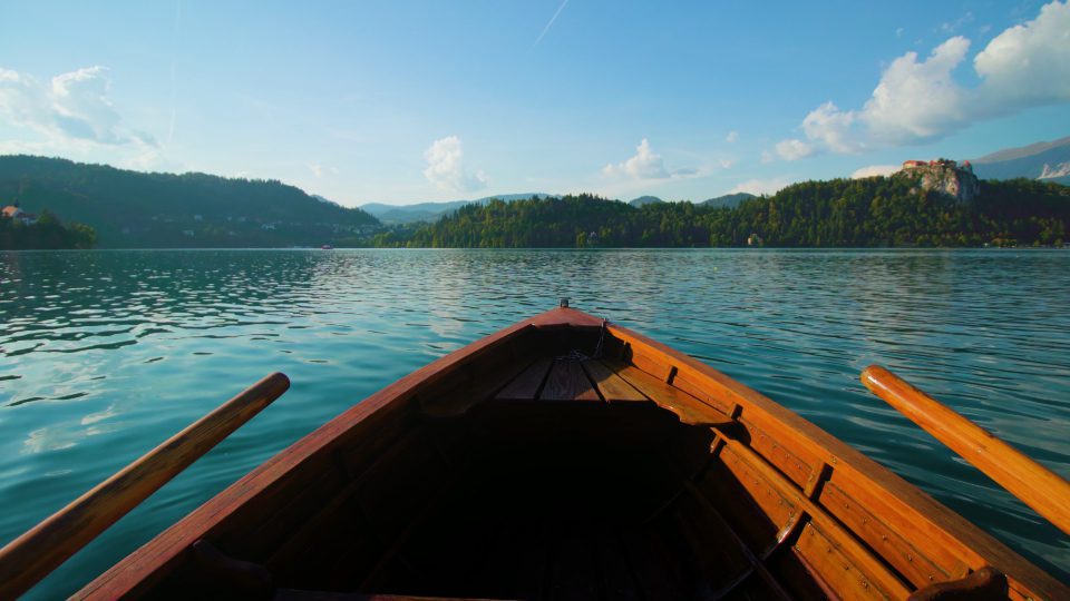 Wooden boat with paddles sailing on water of Bled lake