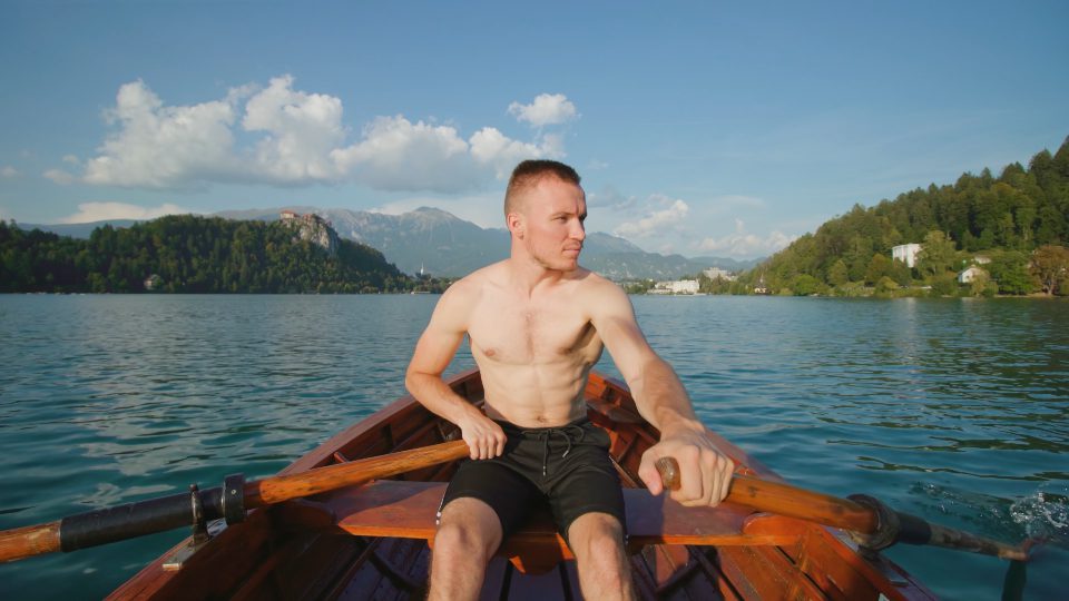 Il giovane controlla le pagaie in barca di legno sul lago di Bled