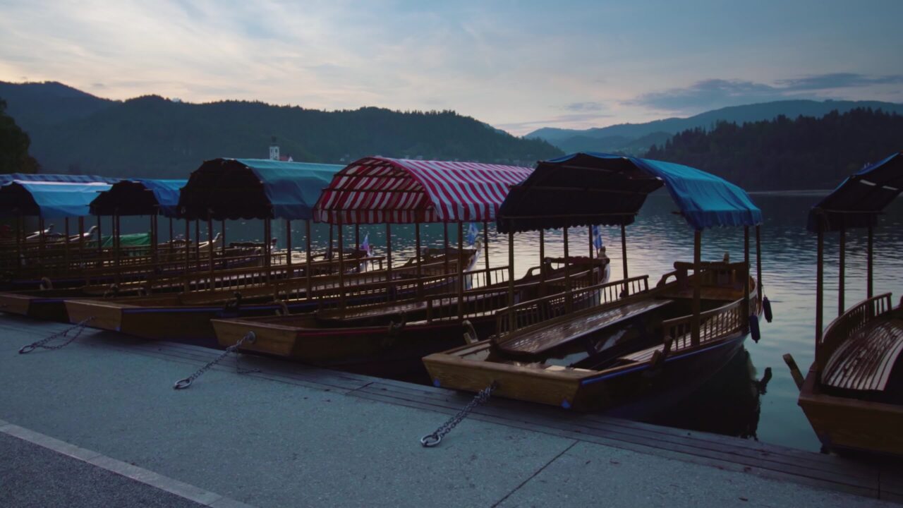 Pletna tradizionale ormeggiata barche in una lunga fila al lago di Bled