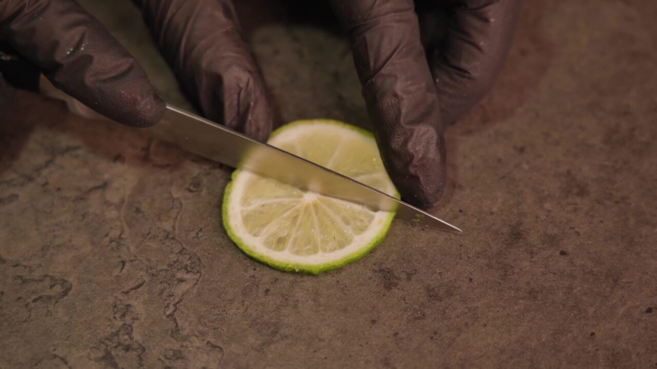 Lo chef taglia la fetta di lime in quarti usando la macro affilata del coltello