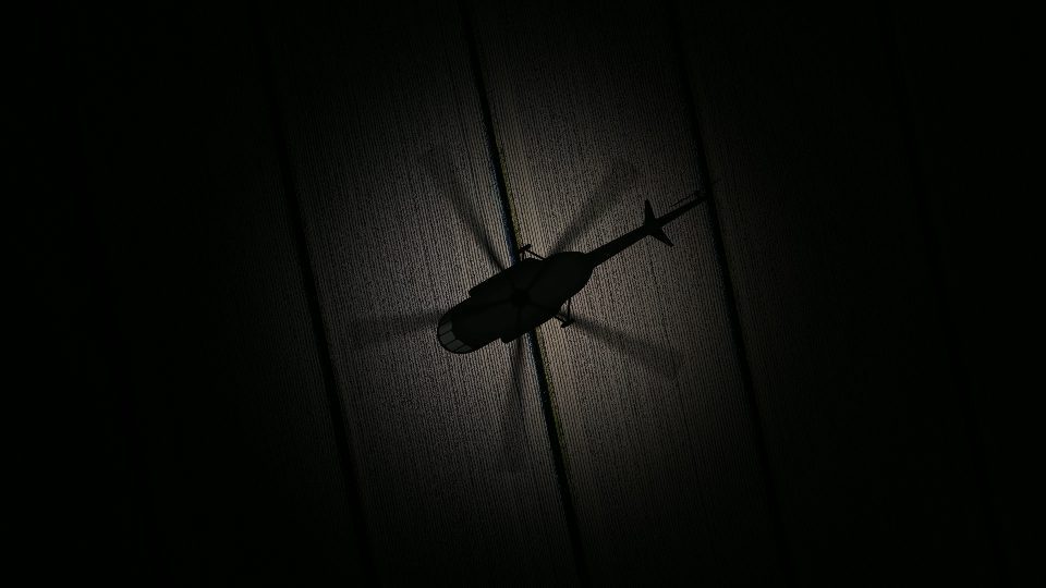Helicopter silhouette flies illuminating wooden background