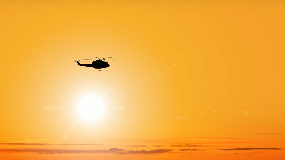 La siluetta scura dell’elicottero vola contro il sole splendente