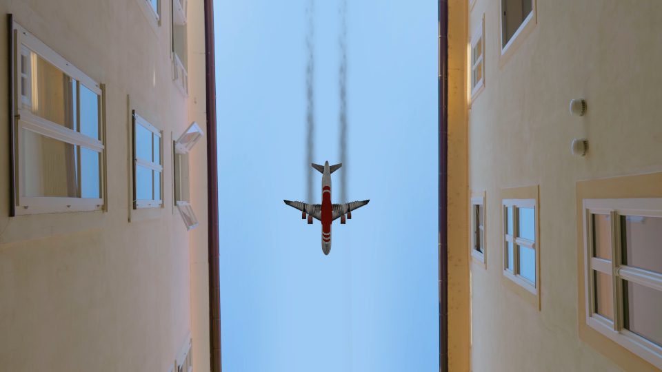 L’aeroplano vola tra gli edifici contro il cielo blu in città