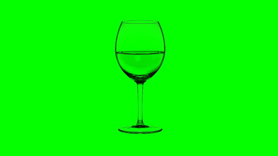 Empty glass filling up with white wine on green background