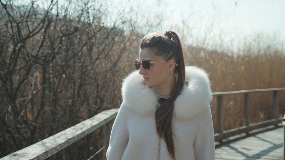 Young woman in sunglasses walks on bridge against mountains