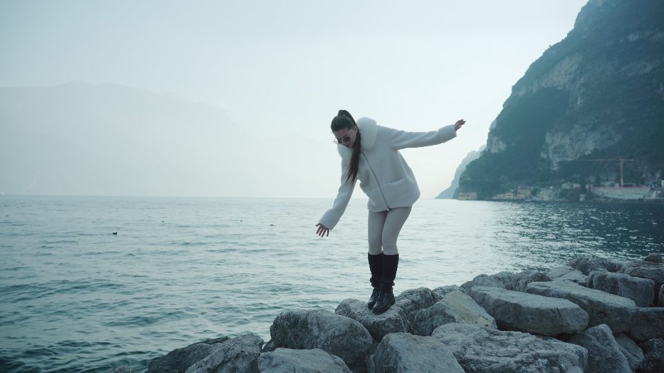 La donna fa un passo su grandi pietre sulla riva del lago di Garda in Italia