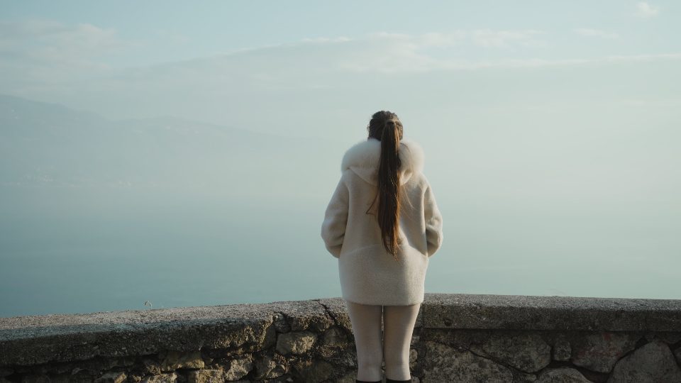 La donna guarda il lago di Garda coperto da una fitta nebbia al mattino