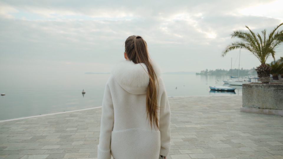 La donna cammina al porto della città guardando il lago di Garda nella foschia