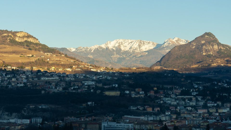 L’ombra copre la città di Trento con gigantesche montagne forestali