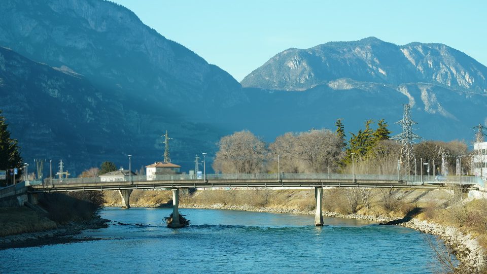 Heavy traffic on bridge built across blue river in Trento