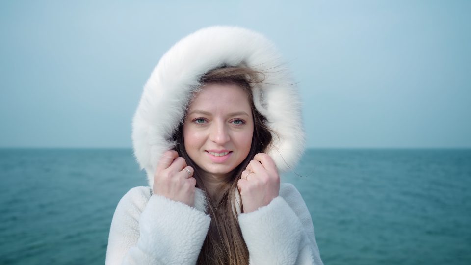 Giovane donna con cappuccio peloso bianco sul il lago di Garda