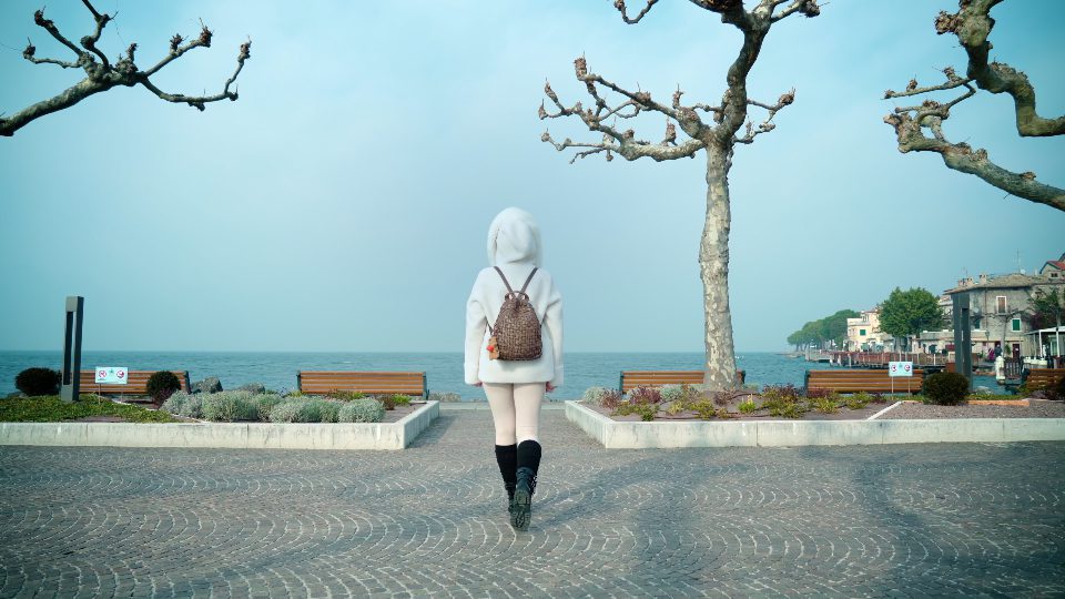 La donna cammina sul terrapieno avvicinandosi al lago di Garda