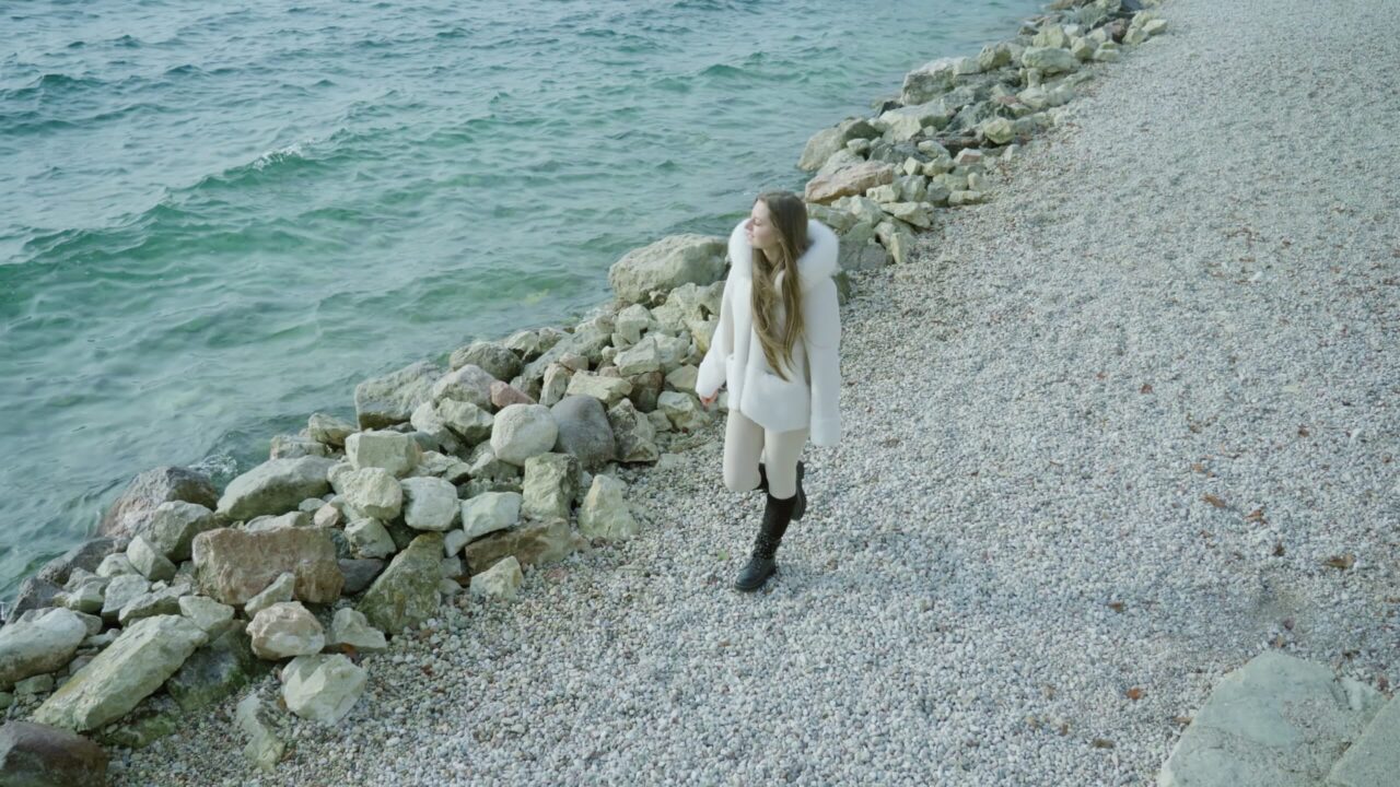 Donna cammina sulla riva vicino alle rocce che guardano il lago
