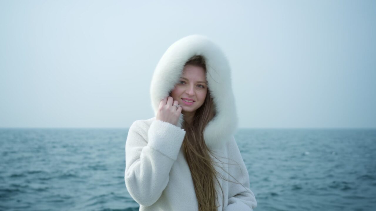 Donna chiude il cappuccio peloso nascondendosi dal vento sul lago di Garda