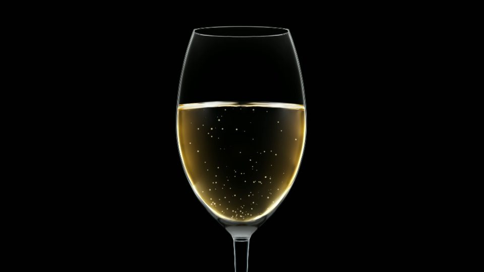 Elegant empty glass fills up with white sparkling wine macro