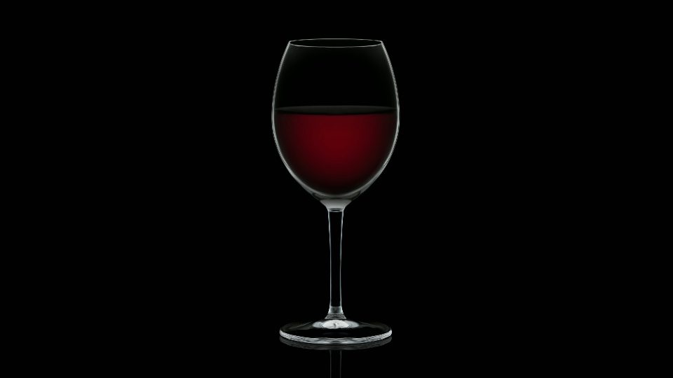 Il bicchiere vuoto di cristallo si riempie di delizioso vino rosso